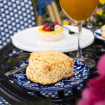 Butter scone on a blue plate with a glass of orange juice in the background.