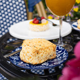 Butter scone on a blue plate with a glass of orange juice in the background.