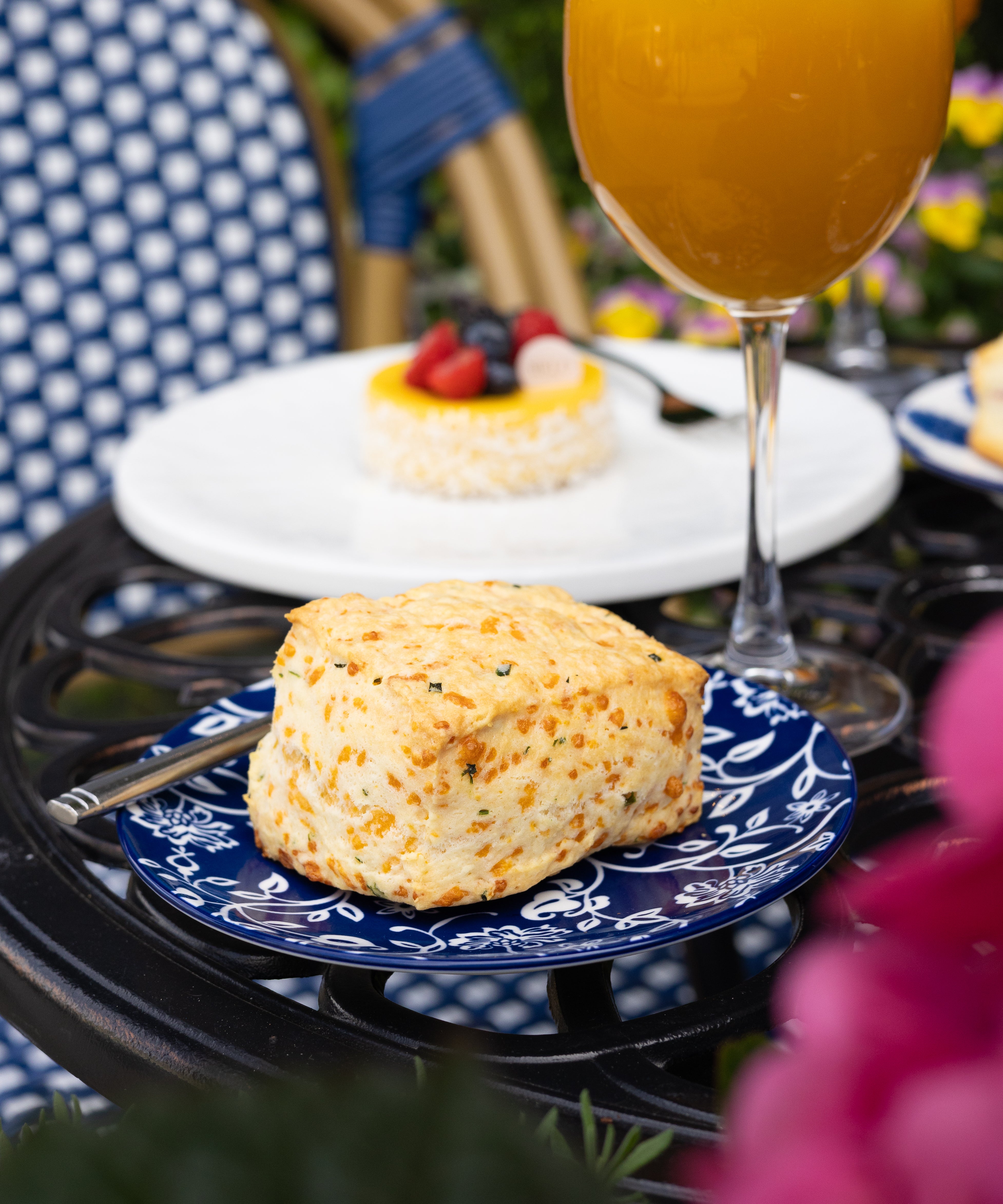 Butter scone on a blue plate with a glass of orange juice in the background.