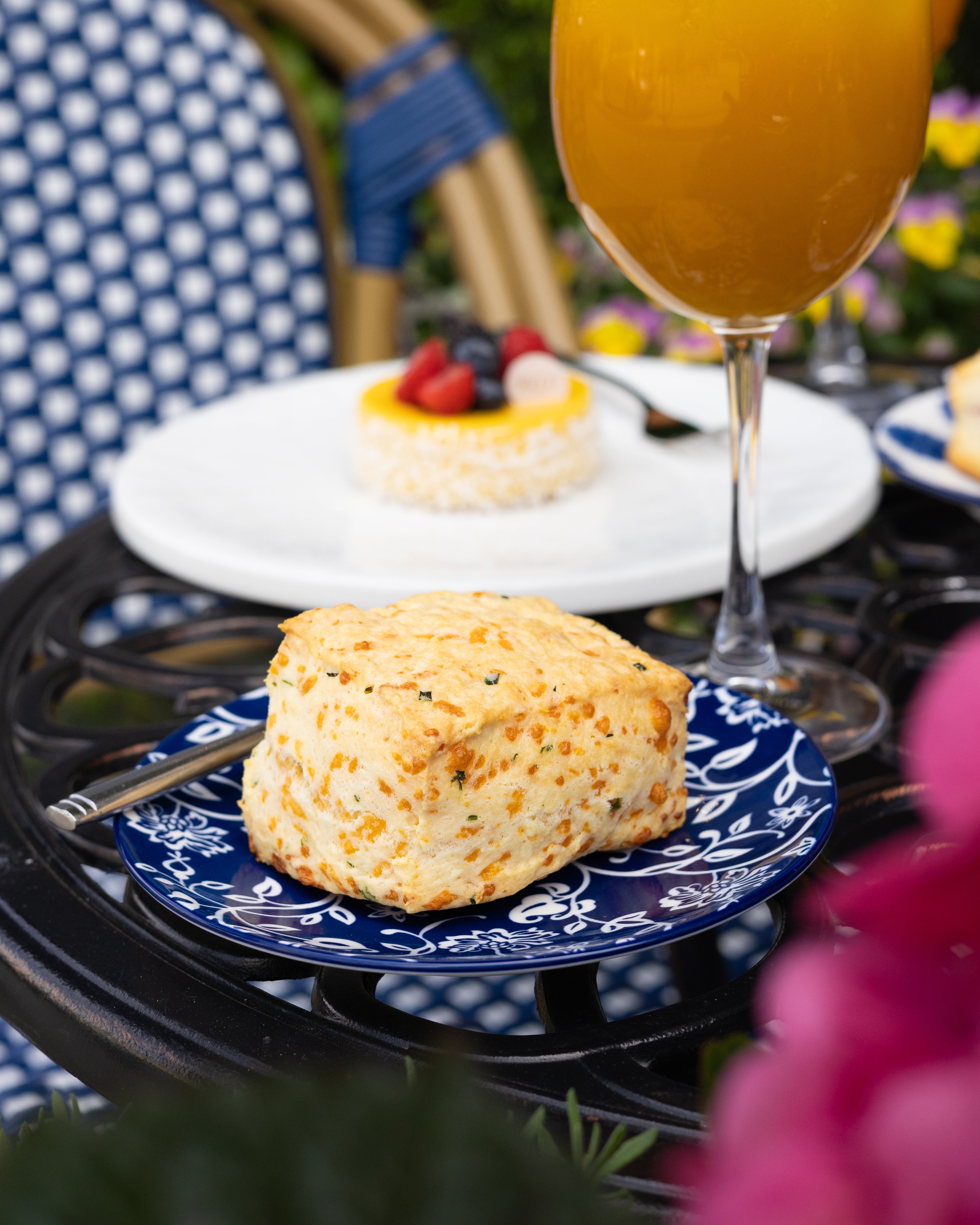 Butter scone on a blue plate with a glass of orange juice in the background.