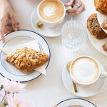 People enjoying pastries and coffee at a table with flowers.