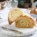 Sliced croissant on a decorative plate with a blurred background