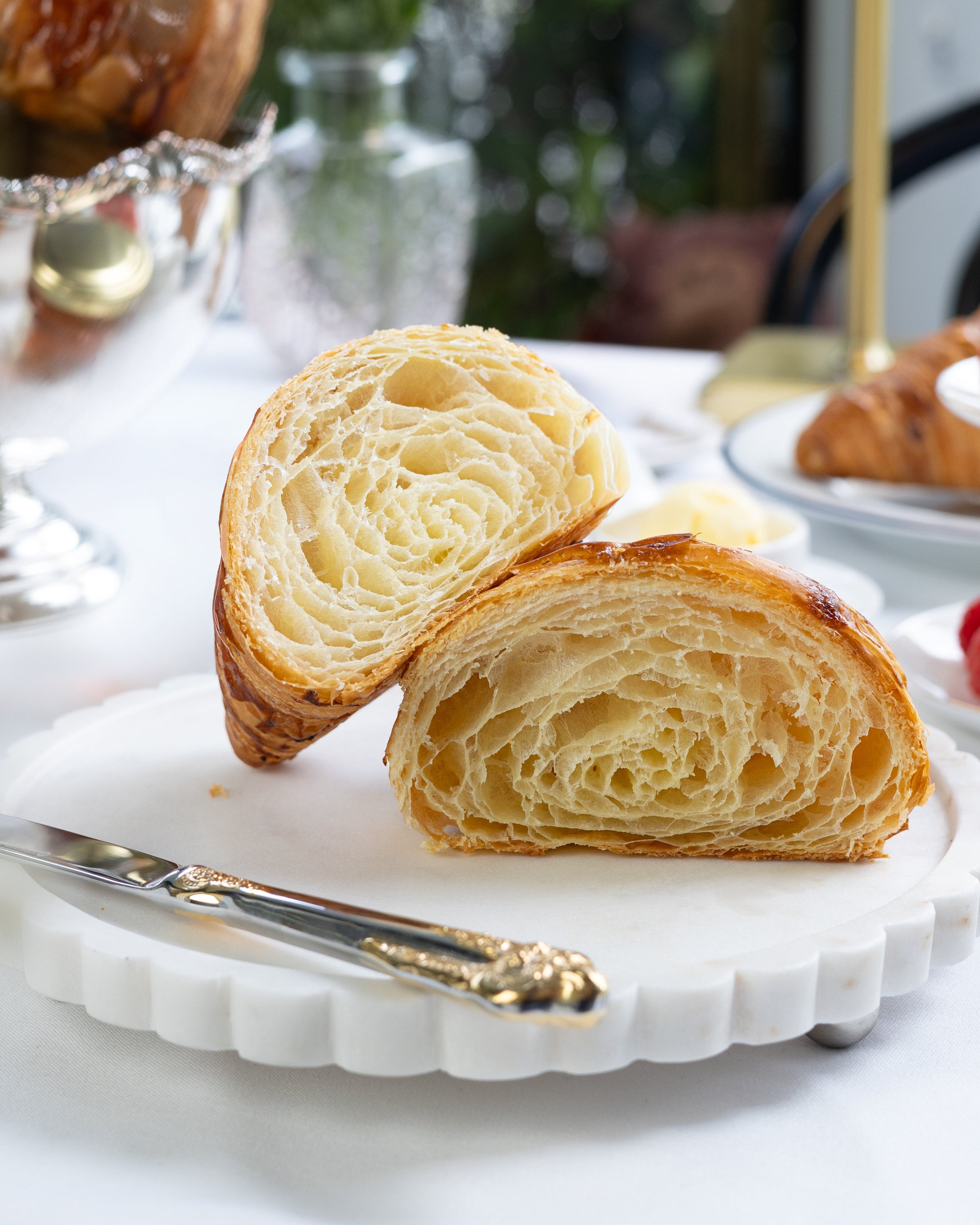 Sliced croissant on a decorative plate with a blurred background