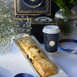 Three scones on a tray with a coffee cup featuring a logo, set against a decorative background.