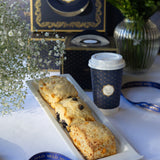 Three scones on a tray with a coffee cup featuring a logo, set against a decorative background.