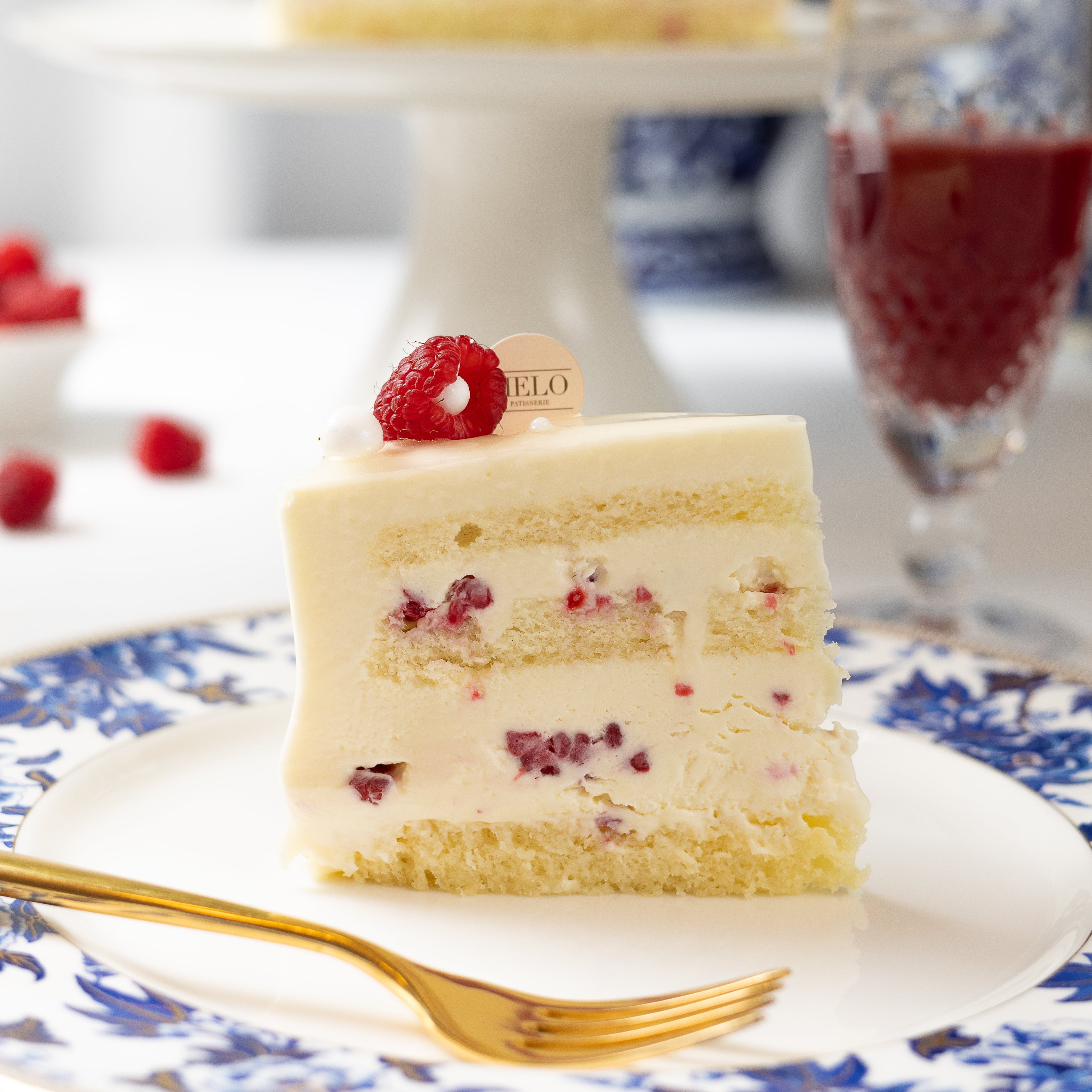 Slice of layered cake with raspberries on a decorative plate with a fork.