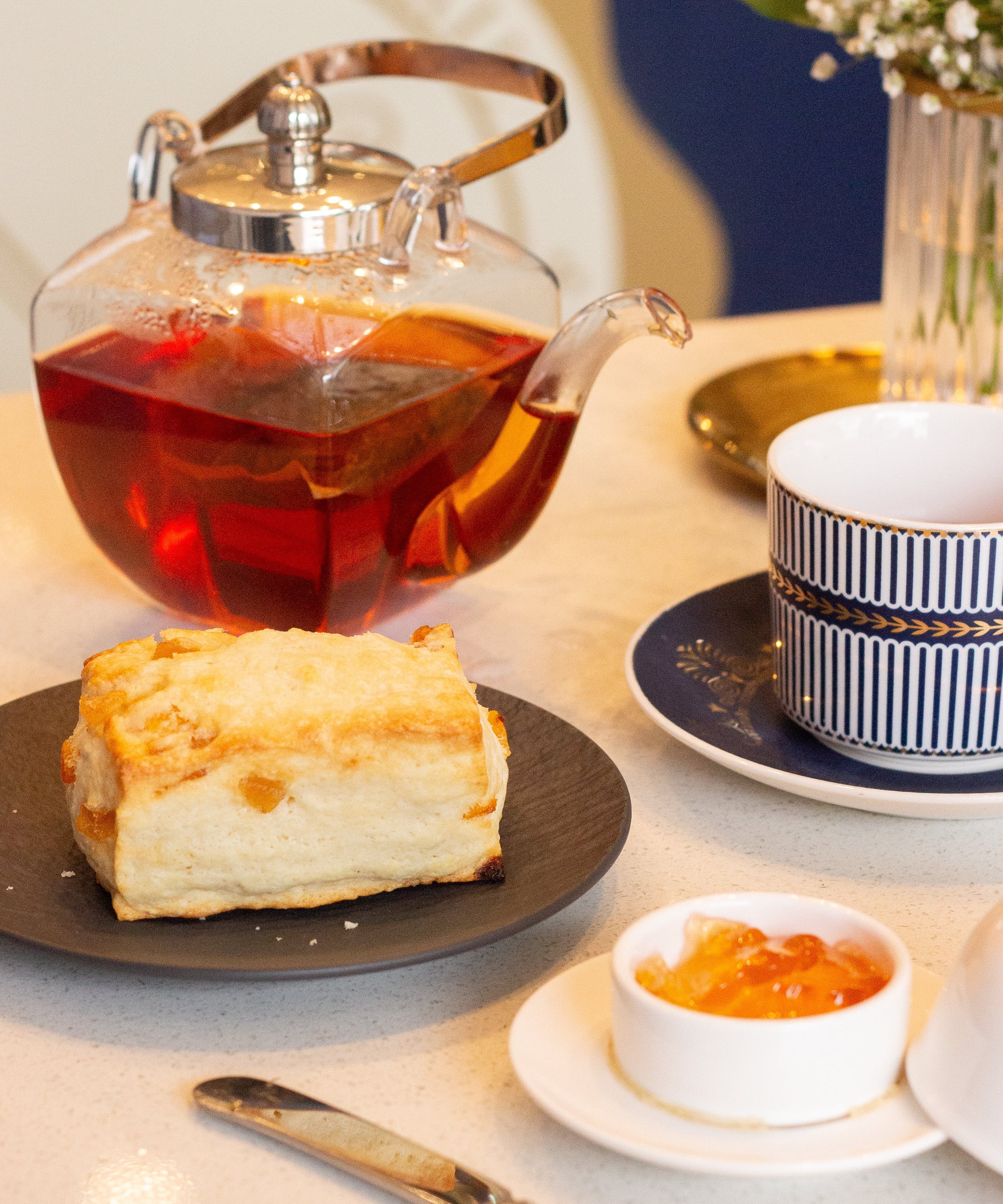 Tea set with a teapot, cup, and plate of cake on a table.