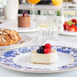 Table setting with a slice of cheesecake, berries, and a glass of orange juice.