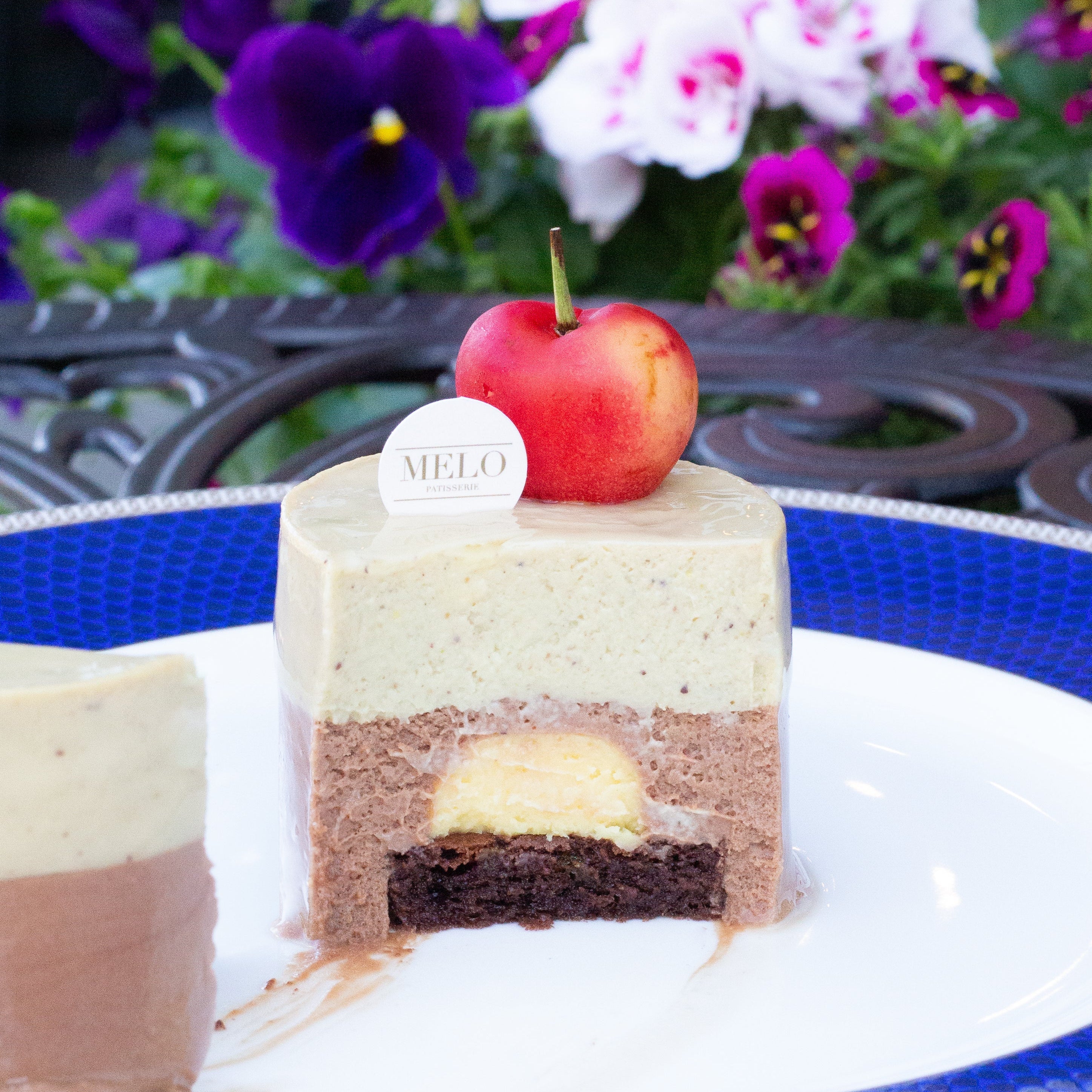 Layered cake on a plate with an apple on top, set against a floral background