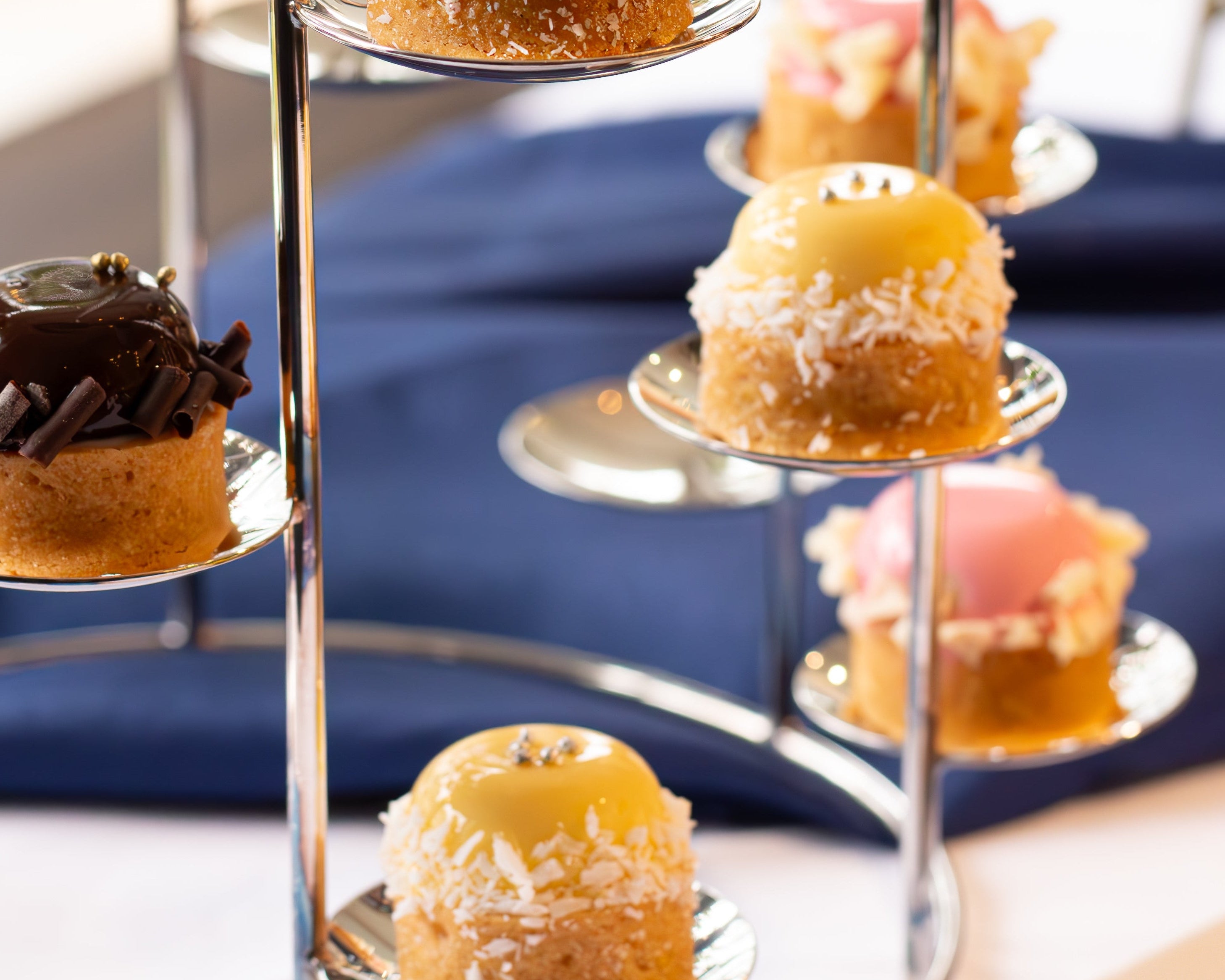 Three-tiered dessert stand with various pastries on a blurred background