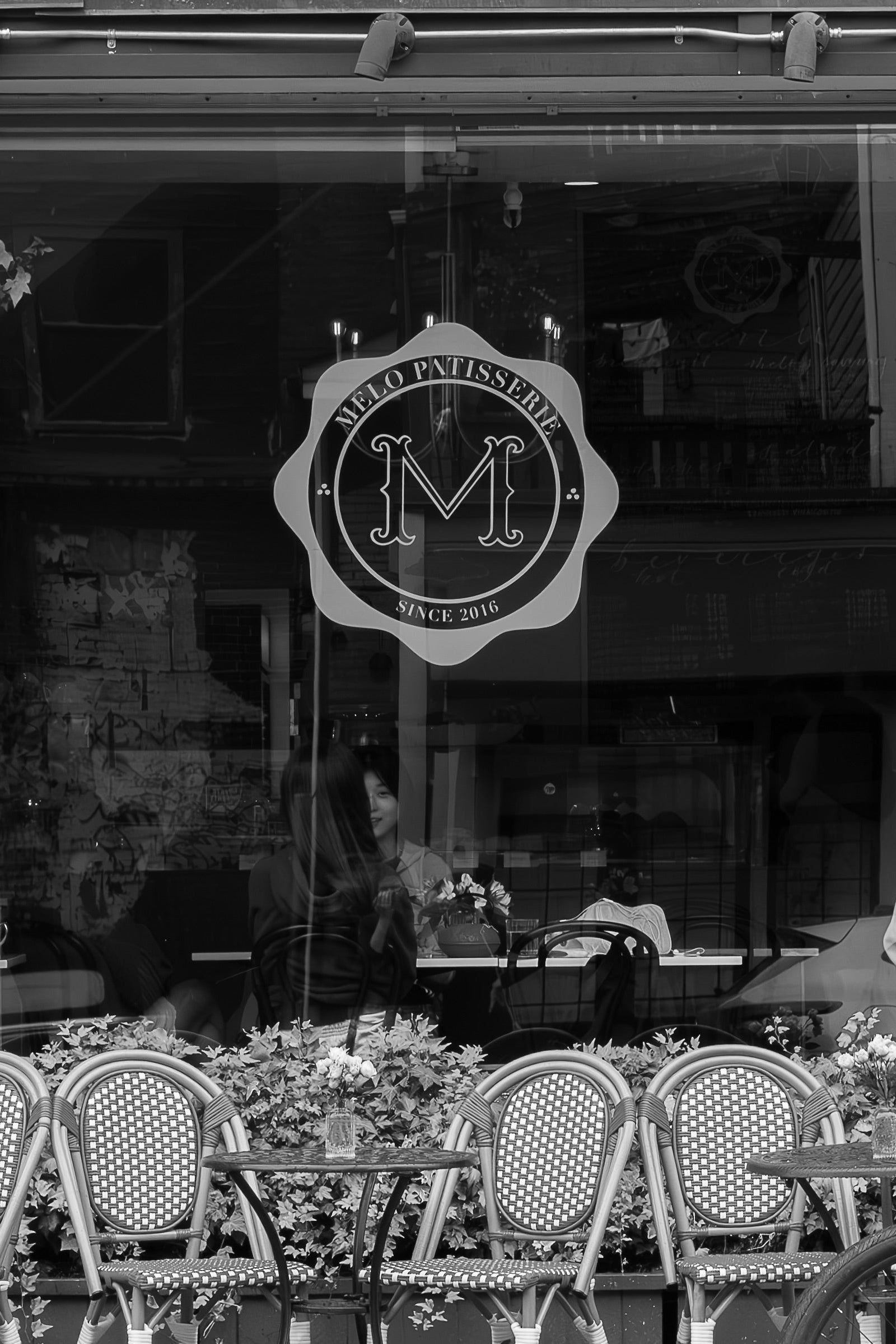 Black and white image of a restaurant entrance with outdoor seating area