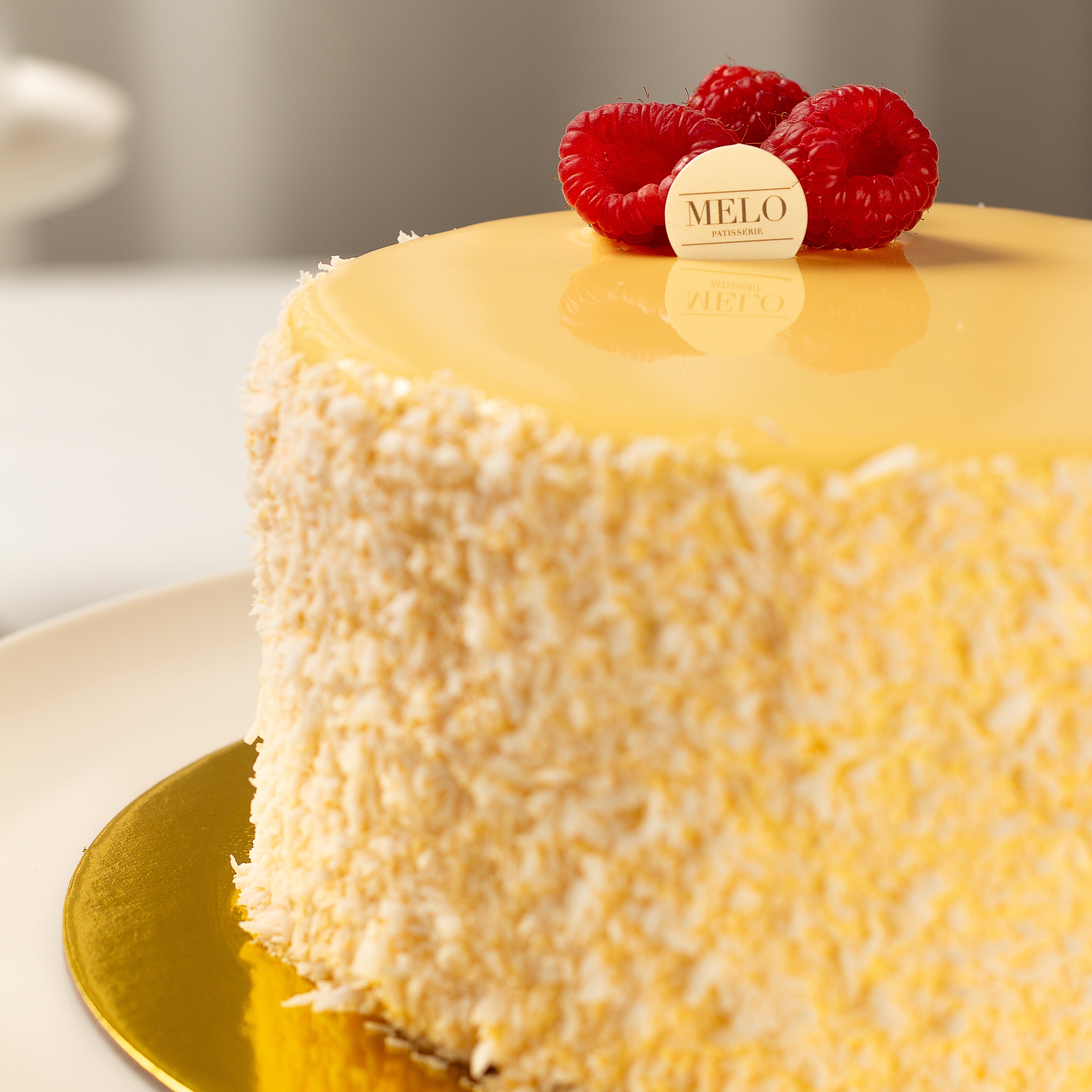 Yellow cake with raspberry decorations on a gold plate