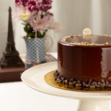 Chocolate cake on a white stand with decorative elements, blurred background