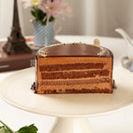 Multi-layered chocolate cake on a white plate with a blurred background