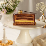 Chocolate mousse cake on a white cake stand with decorative elements