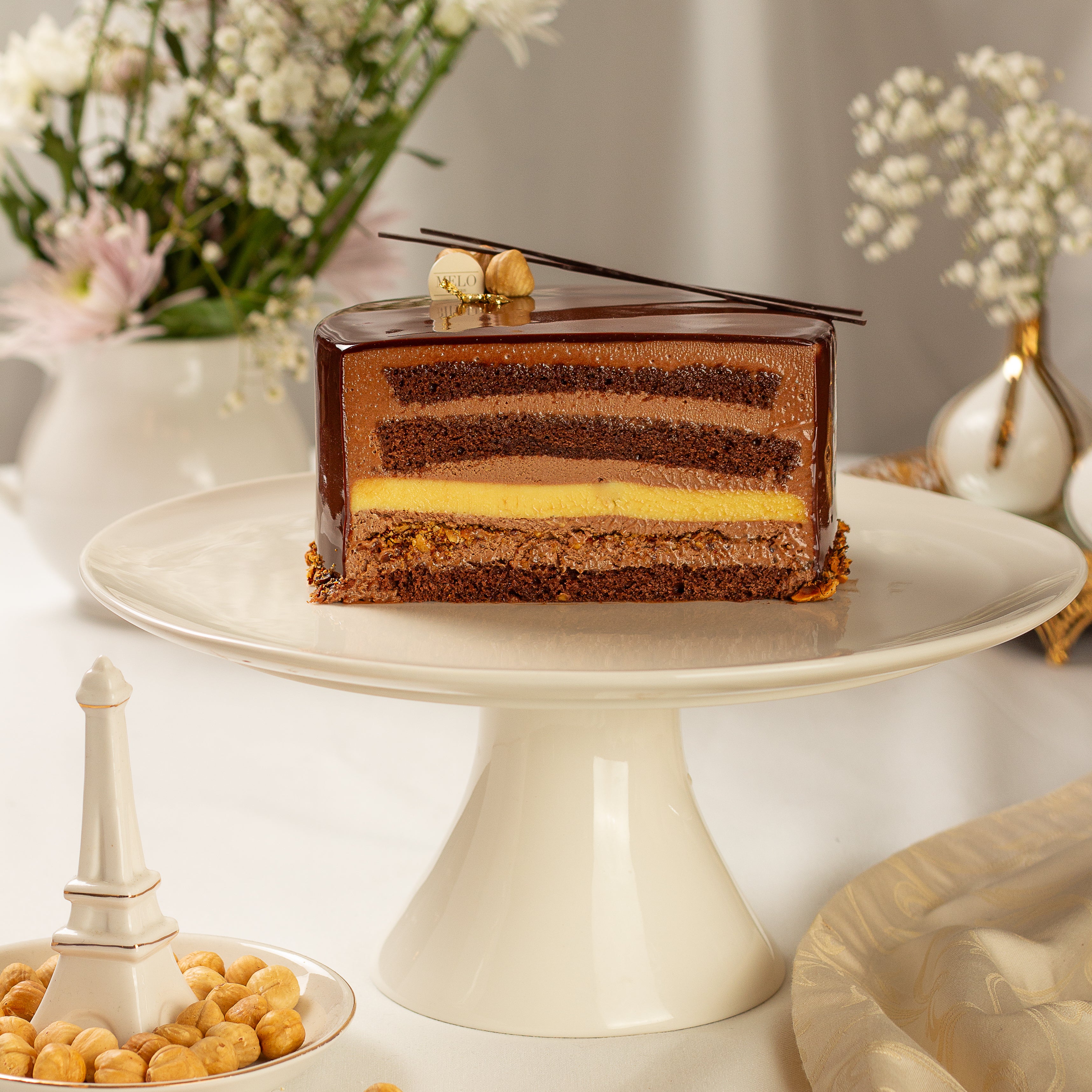 Chocolate mousse cake on a white cake stand with decorative elements