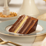 Slice of layered chocolate cake on a decorative plate with a blurred background