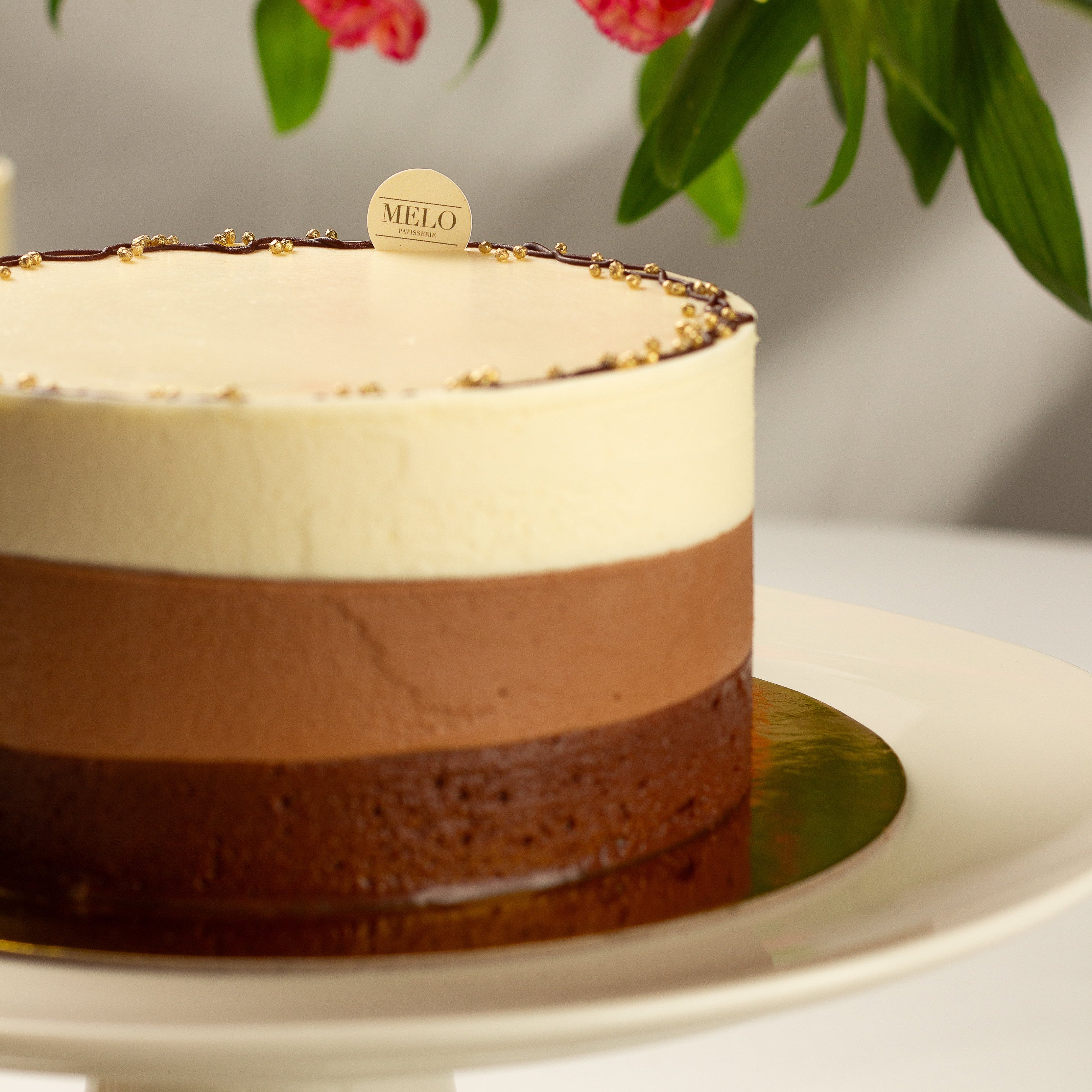 Chocolate mousse cake on a white plate with flowers in the background