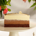 Layered cake on a white stand with flowers in the background