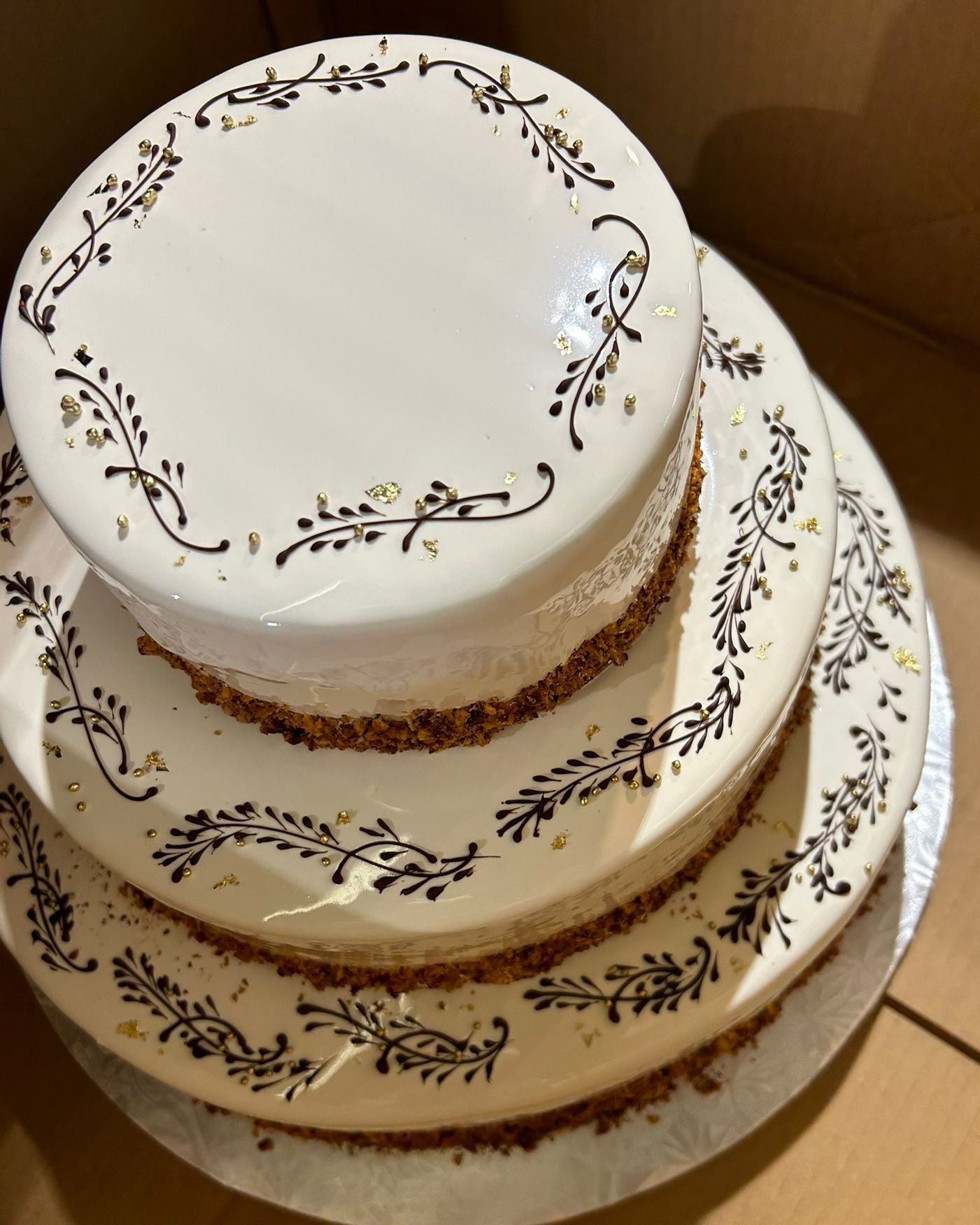 Three-tiered cake with decorative patterns on a wooden surface