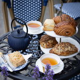 Tea set with scones and pastries on a table outdoors