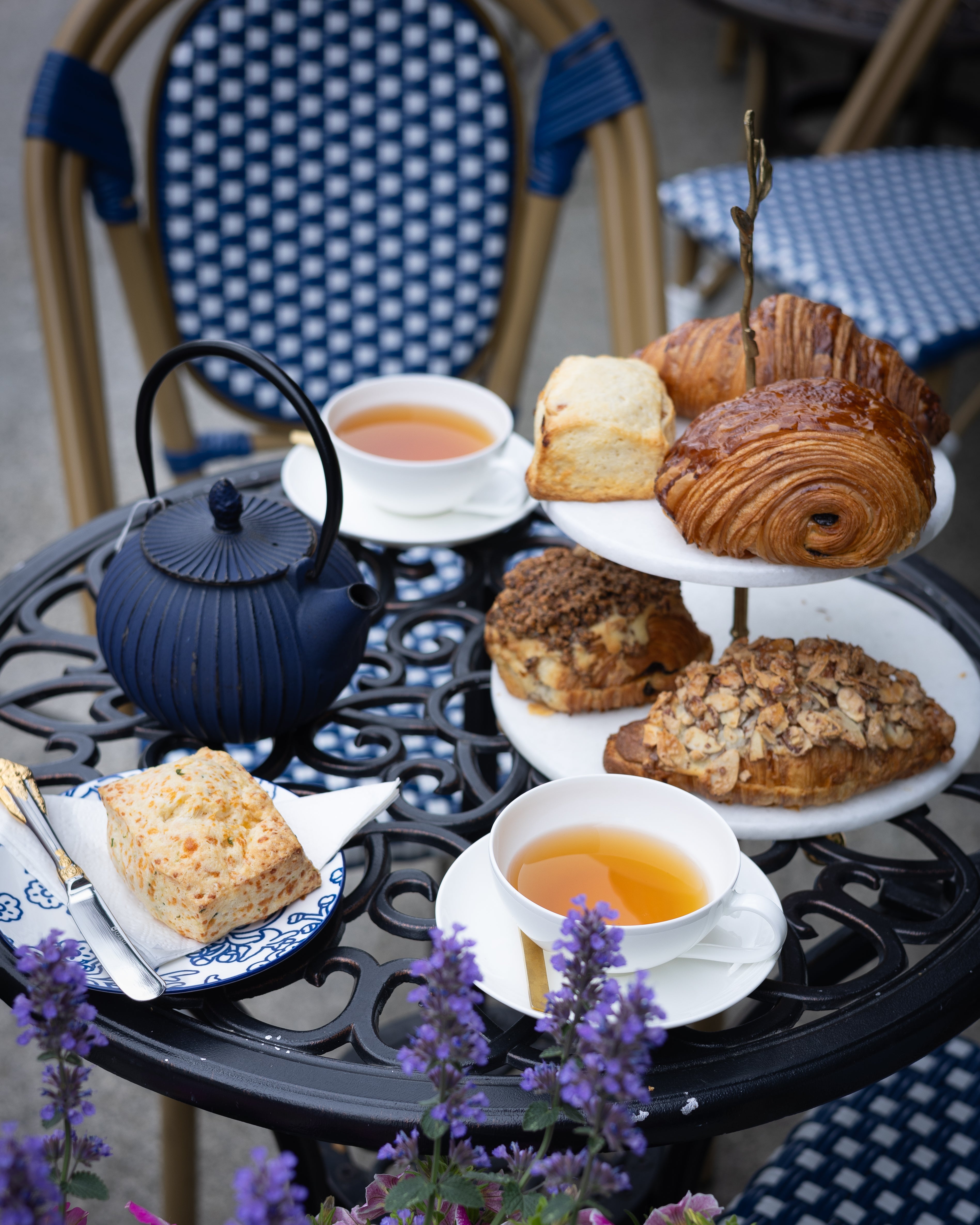 Tea set with scones and pastries on a table outdoors