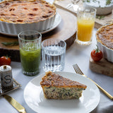 Slice of pie on a plate with drinks and utensils on a table