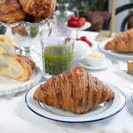 Croissants on a plate with a glass of green juice on a marble table.