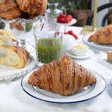 Croissants on a plate with a glass of green juice on a marble table.