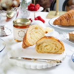 Pastries on a white plate with a jar of jam and a blurred background