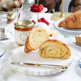 Pastries on a white plate with a jar of jam and a blurred background