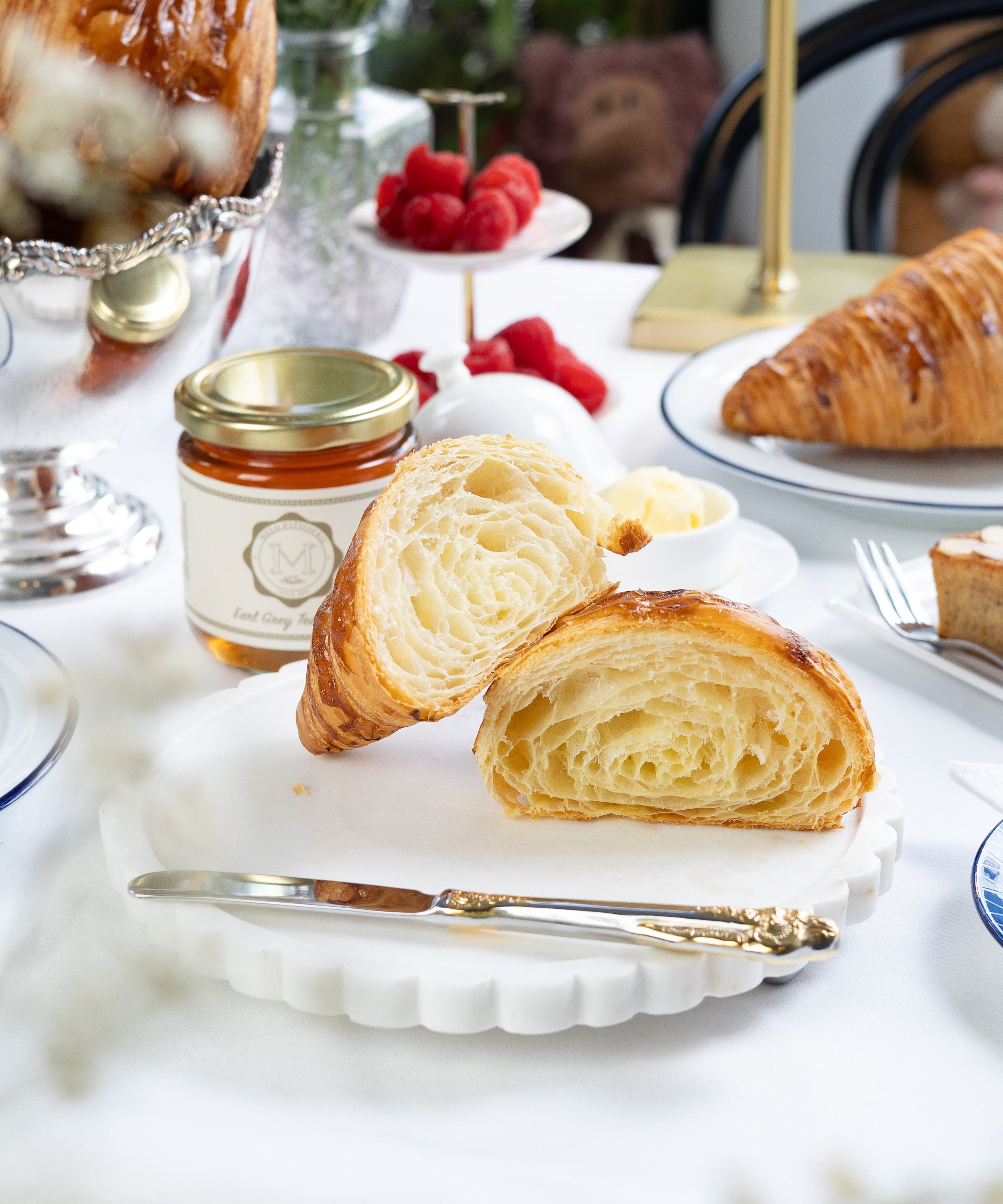 Pastries on a white plate with a jar of jam and a blurred background
