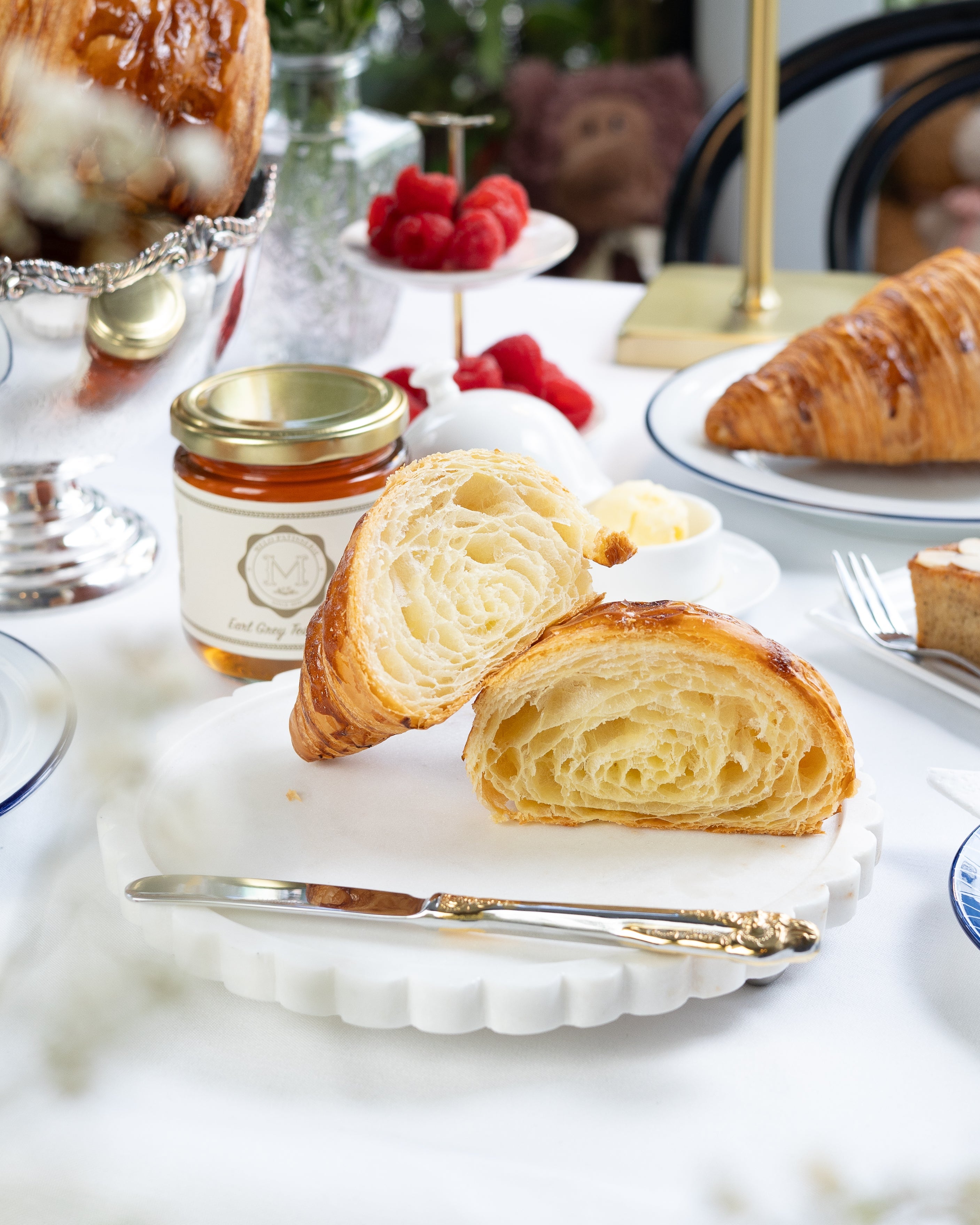 Pastries on a white plate with a jar of jam and a blurred background