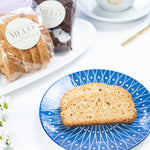 Biscotti on a blue plate with a cup of coffee and packaged pastries in the background.