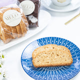 Biscotti on a blue plate with a cup of coffee and packaged pastries in the background.
