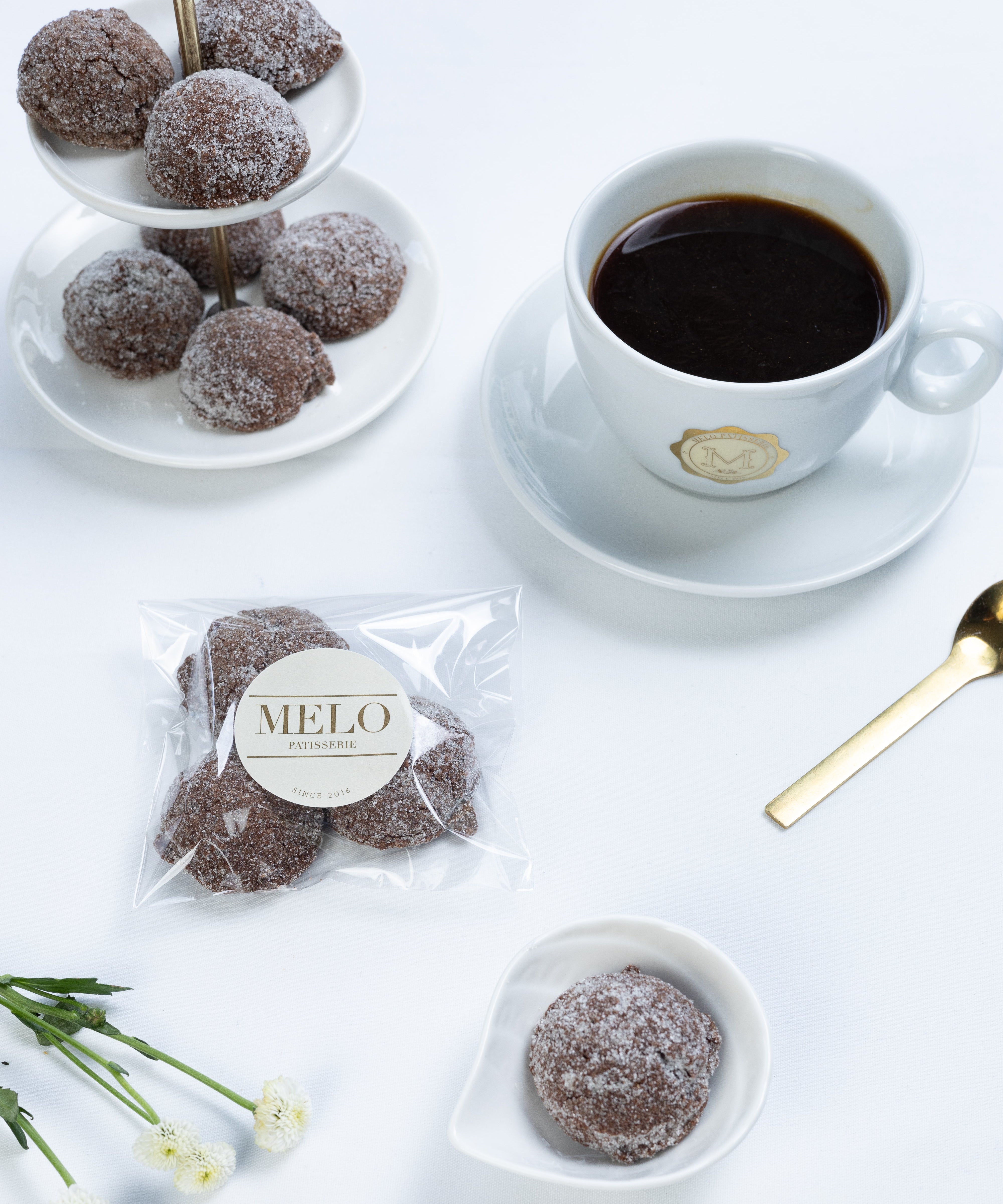 Almond earl grey cookies with a cup of coffee on a white surface, featuring the brand 'Melo'.