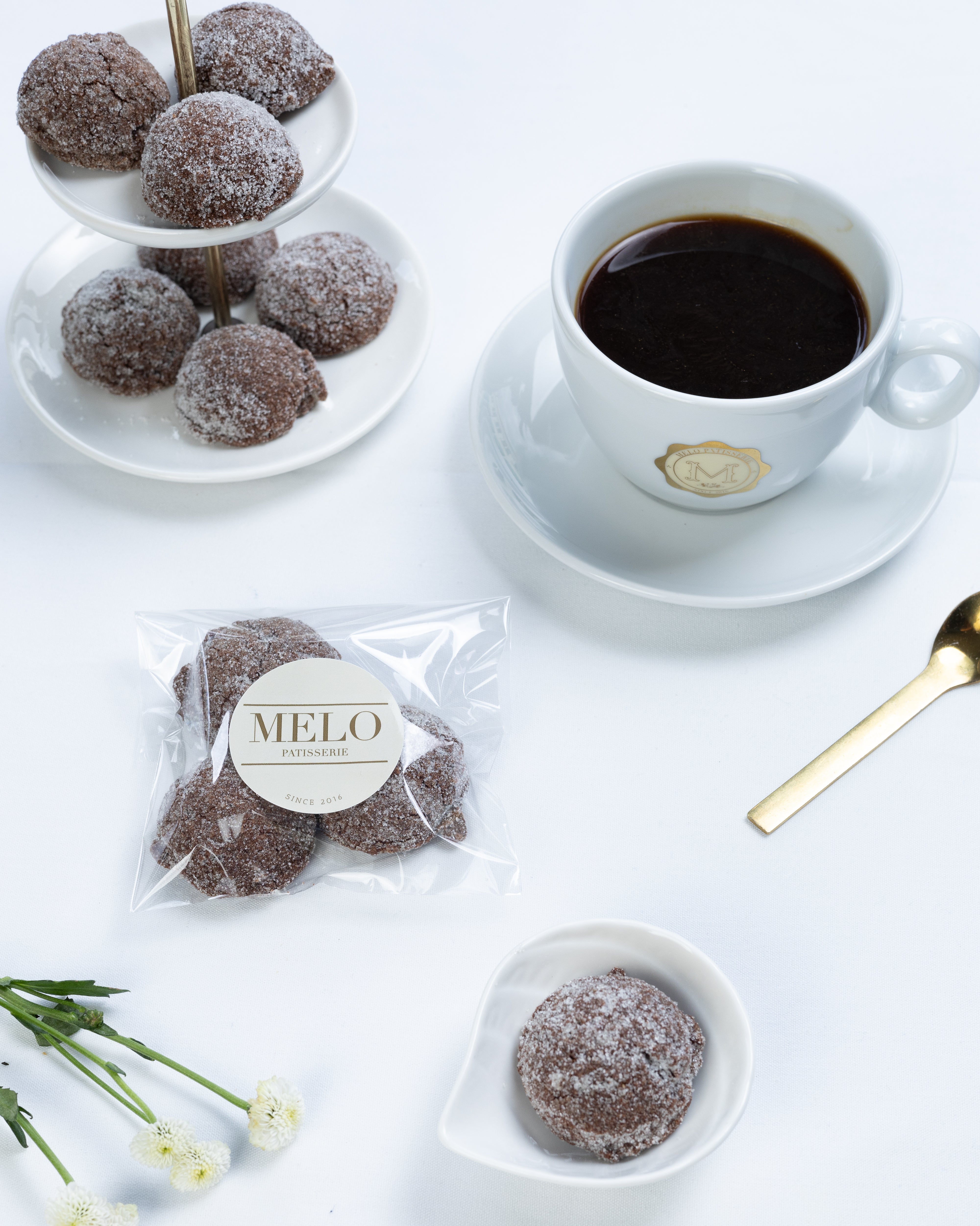 Almond earl grey cookies with a cup of coffee on a white surface, featuring the brand 'Melo'.