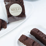 Chocolate biscotti with 'Melo' branding on a white surface