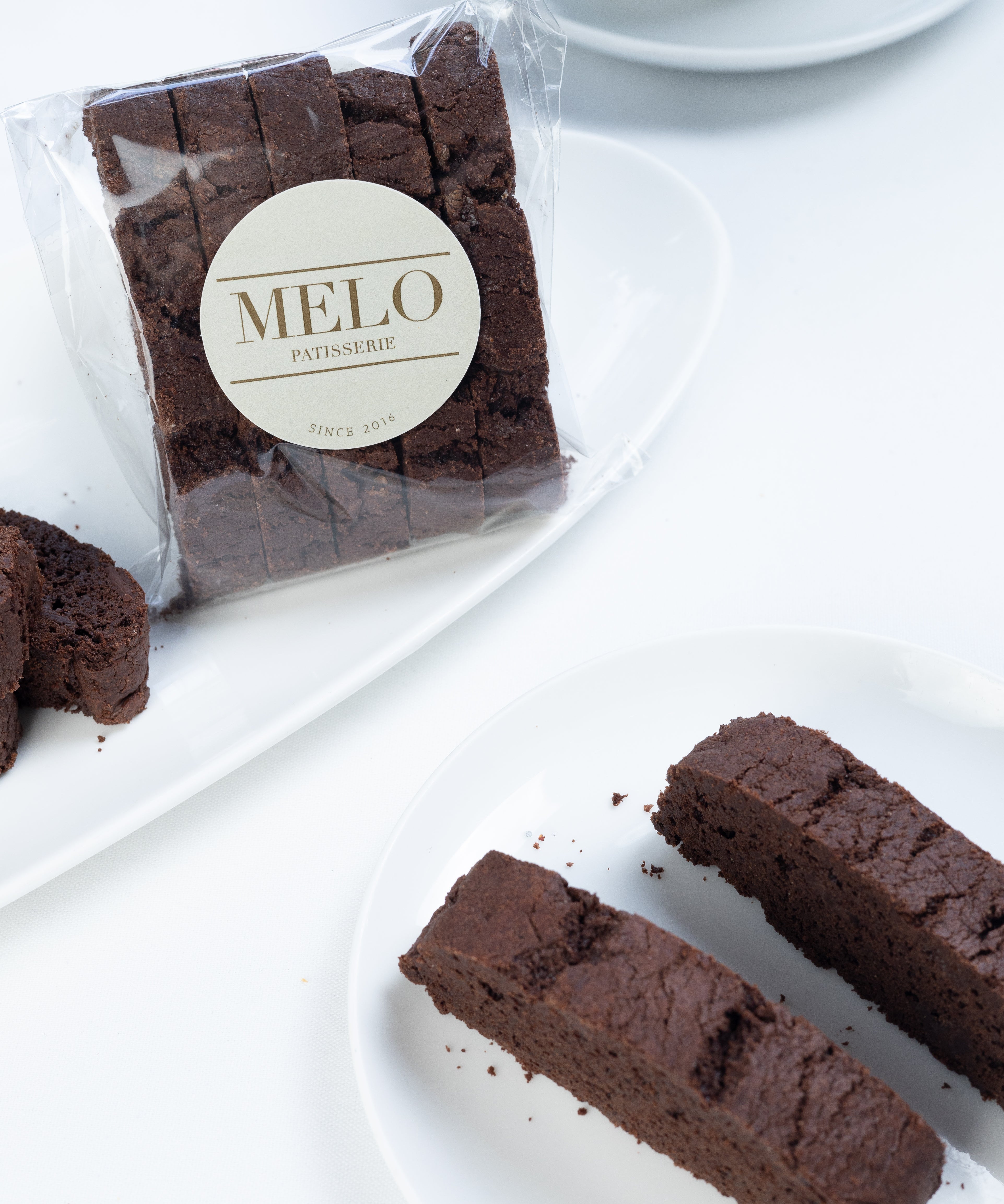 Chocolate biscotti with 'Melo' branding on a white surface