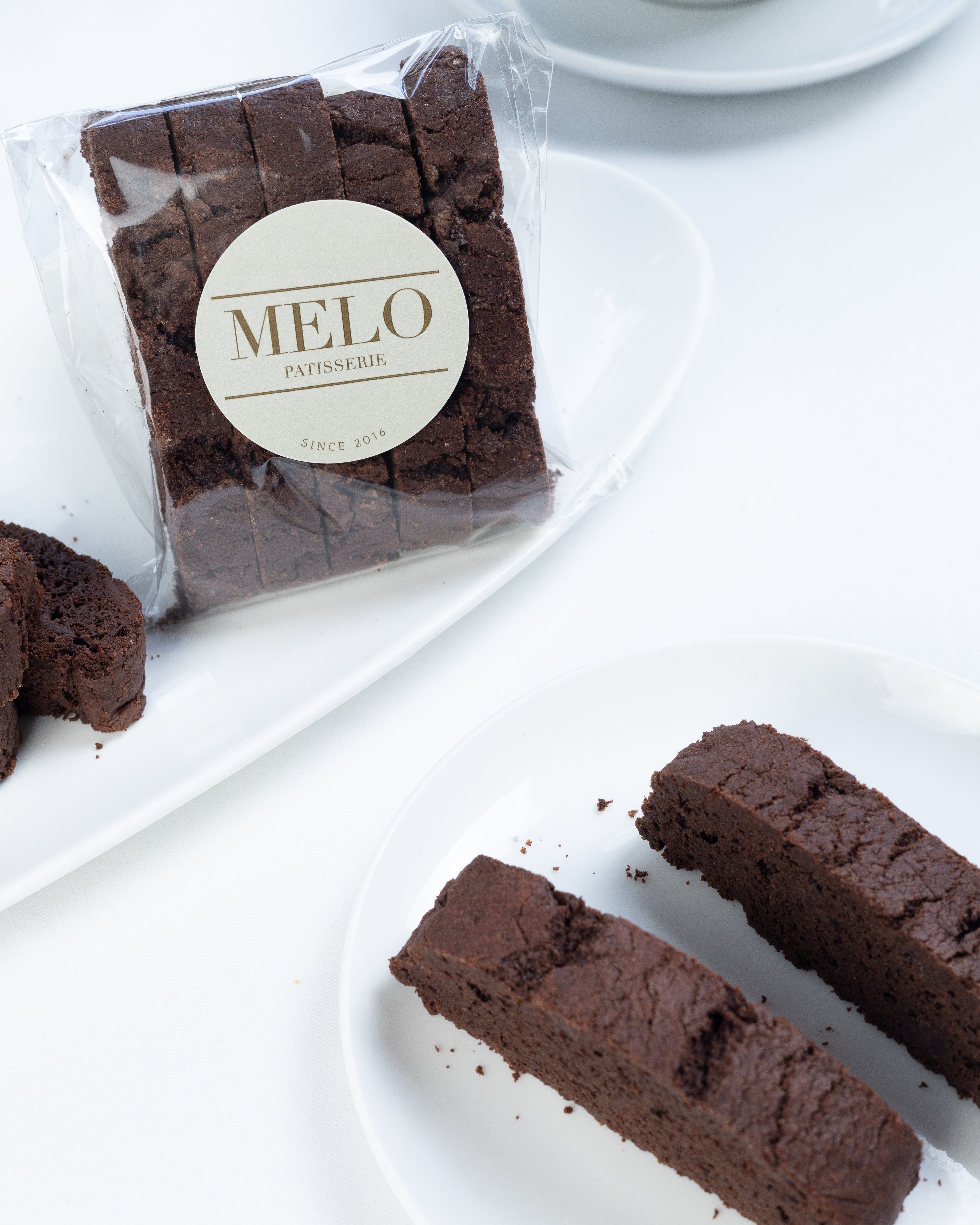 Chocolate biscotti with 'Melo' branding on a white surface