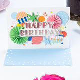 Colorful birthday card with decorative elements on a white surface with pink roses.