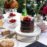 Table setting with a chocolate cake, cookies, and a Chanel menu in an outdoor setting.