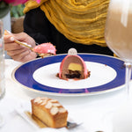 Person eating dessert at a table with a colorful plate and floral background