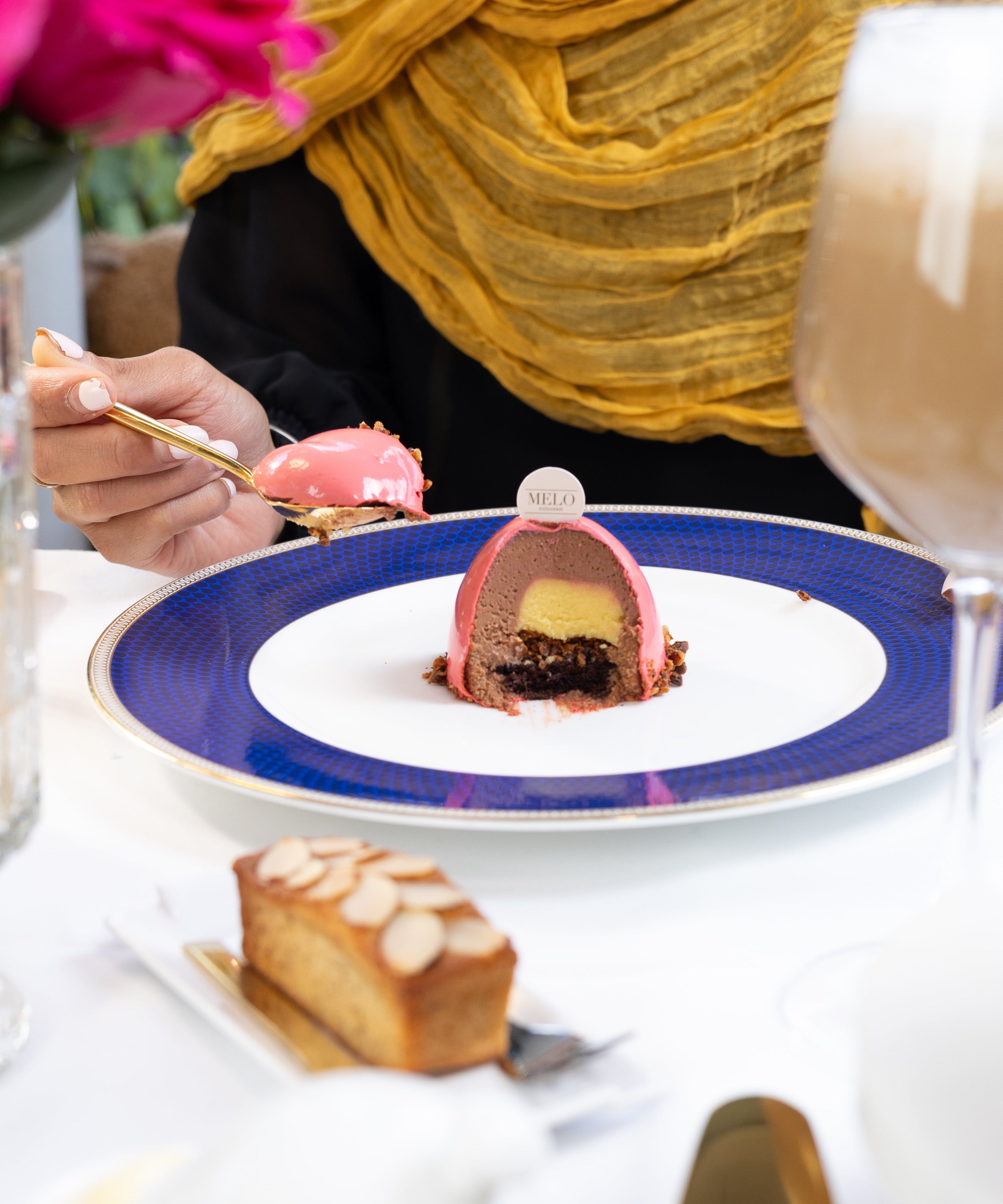 Person eating dessert at a table with a colorful plate and floral background