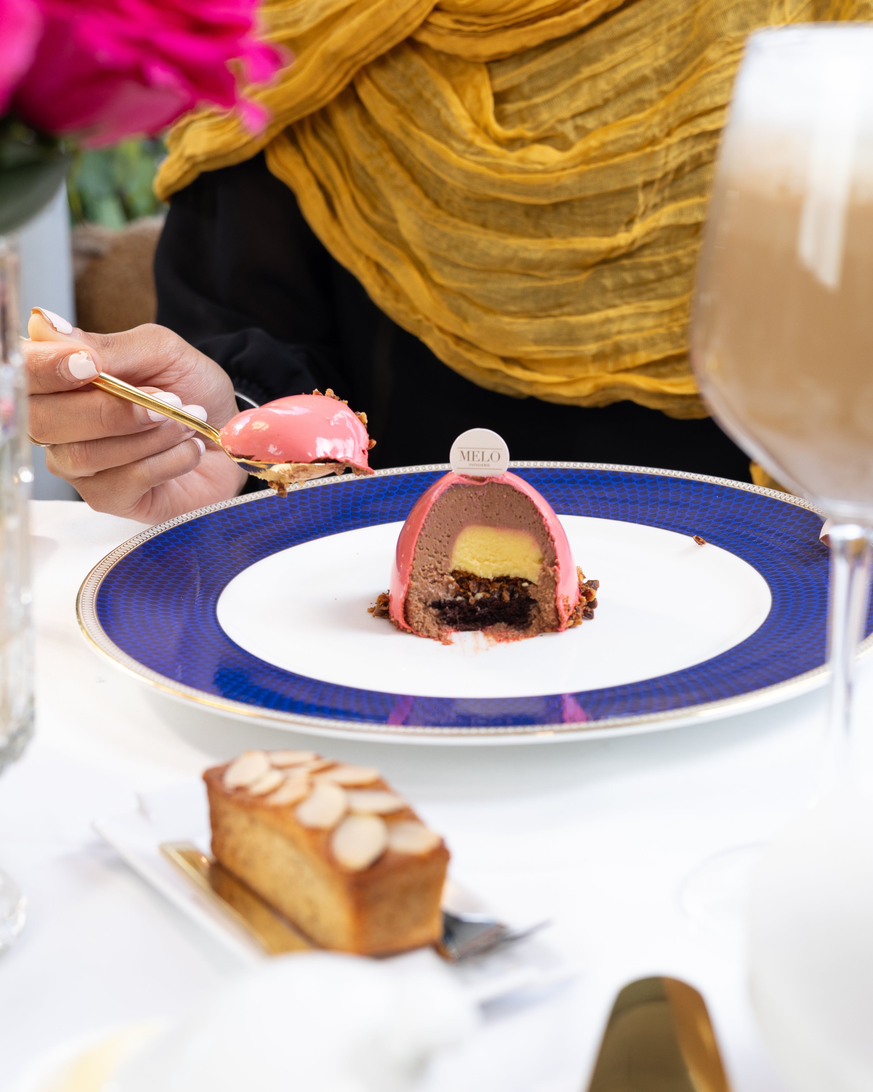 Person eating dessert at a table with a colorful plate and floral background